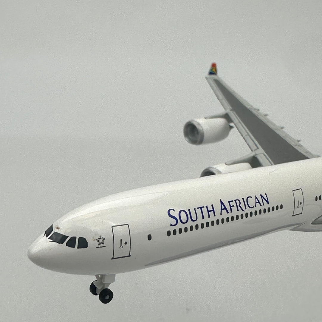 South African Airways airplane flying against a gray sky