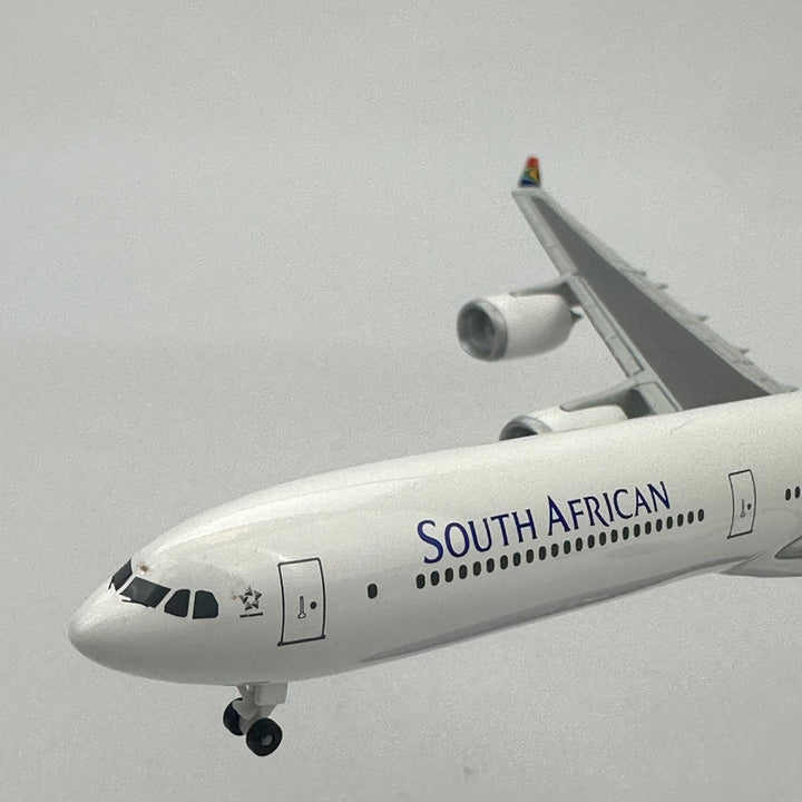 South African Airways airplane flying against a gray sky